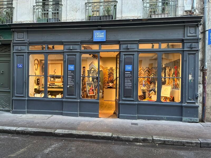 Exterior view of a dark grey storefront with large, brightly lit display windows and a central entrance.