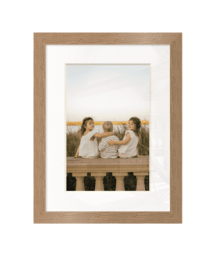 Three children sitting together on a stone wall, framed in light wood.