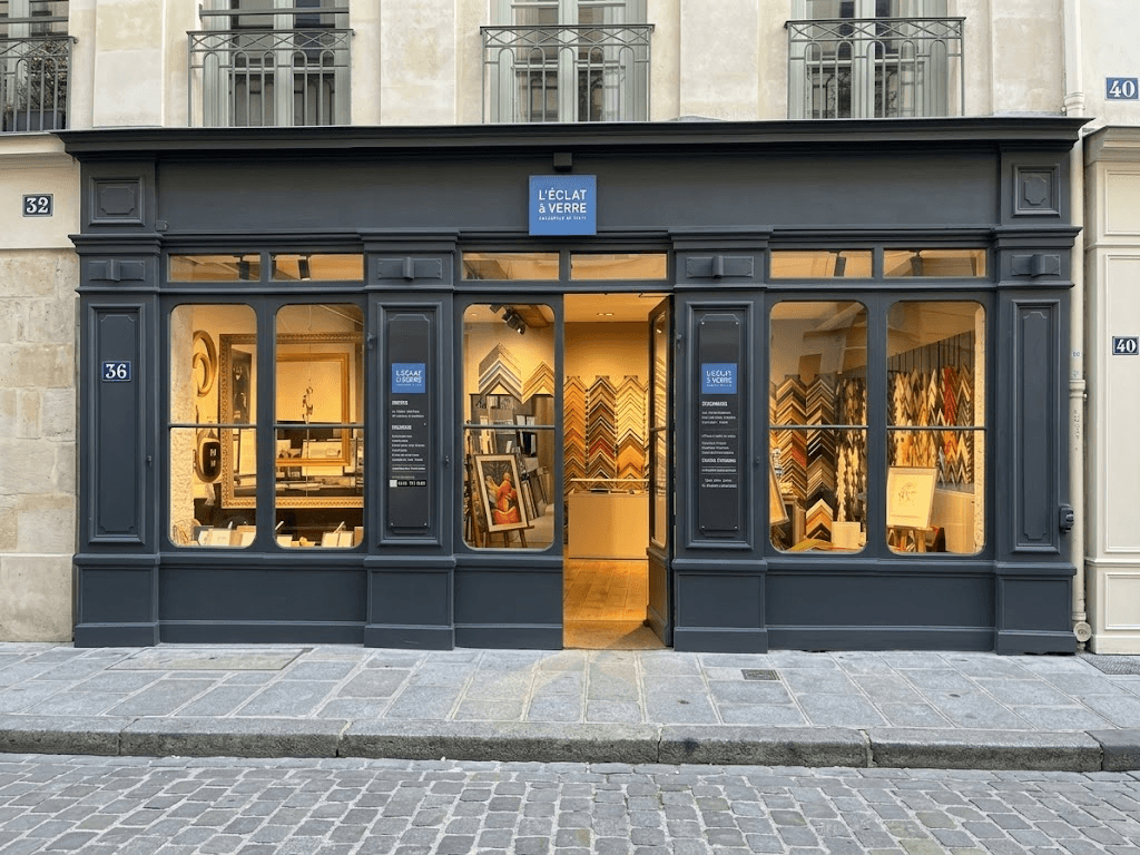 Elegant dark grey Parisian storefront of Eric Coatalem gallery with display windows and open door.