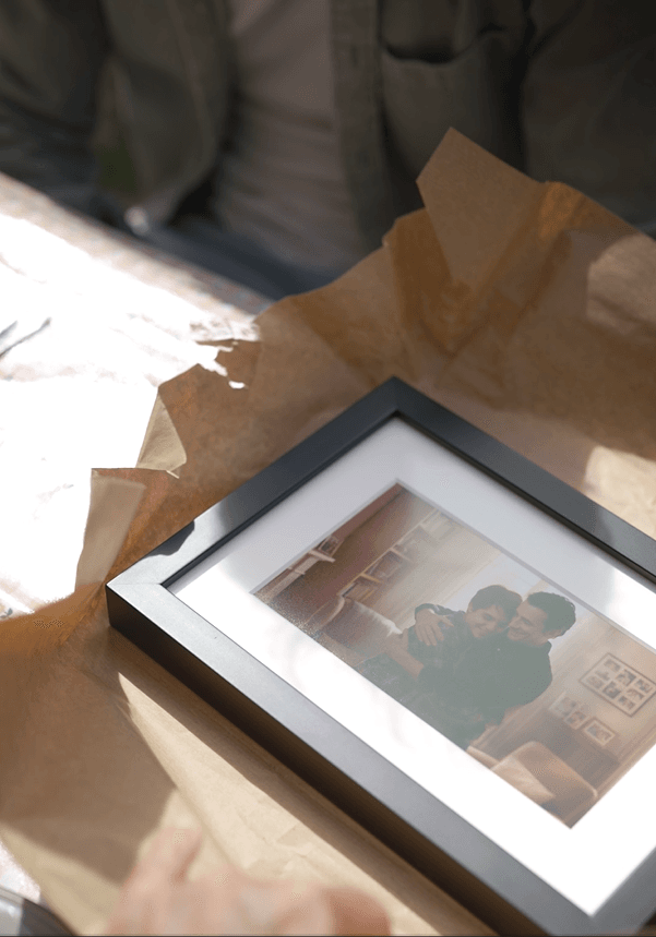 Black framed photo with white mat showing three smiling people on brown paper.