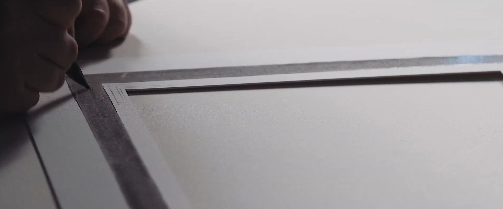 A hand uses a pen and ruler to draw a precise line on white paper.