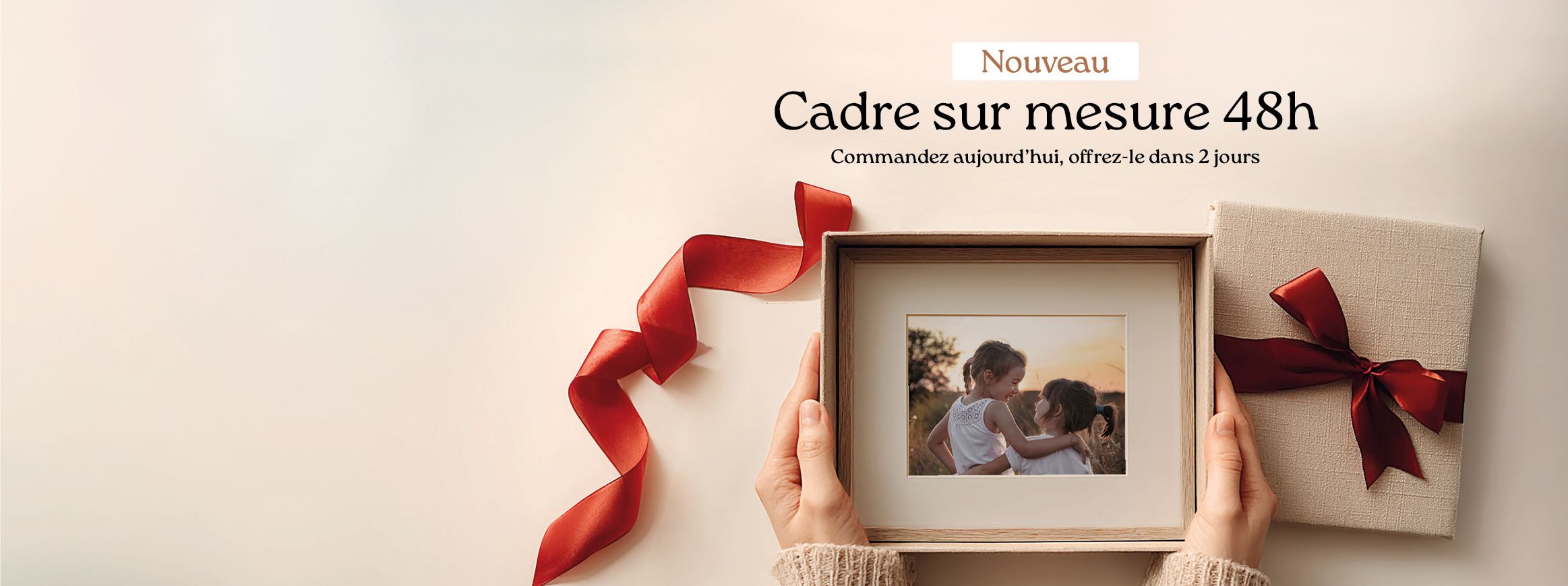 Hands opening a gift box containing a framed photo of children. Custom frame service in 48 hours.