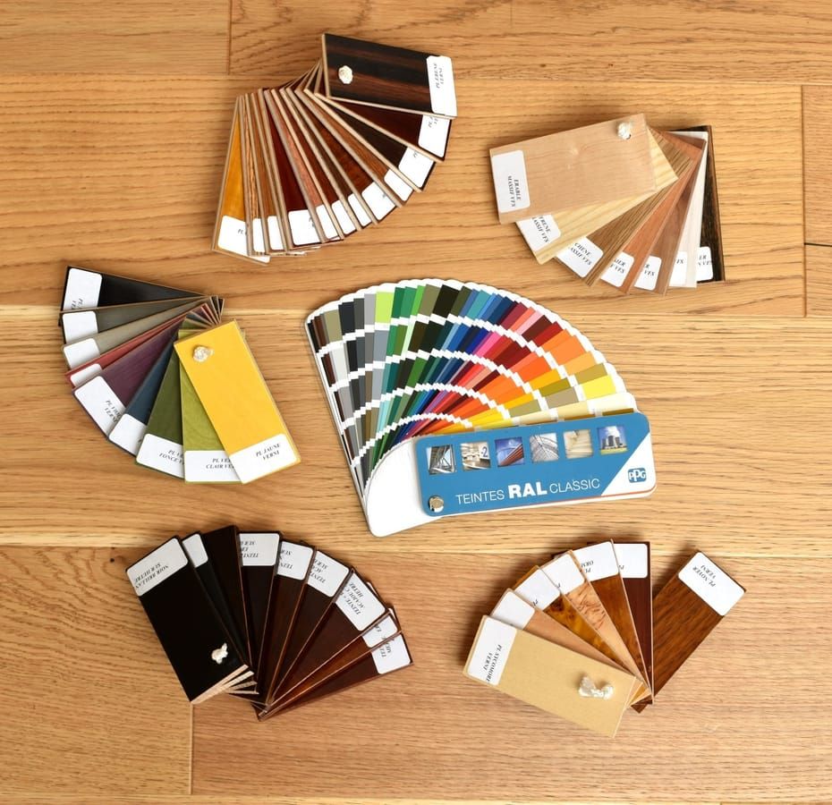 Color swatch fans and paint samples are spread across a light wooden floor.