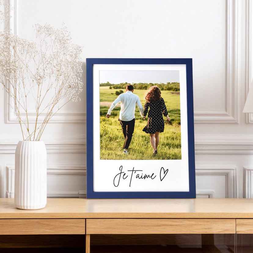 Un couple se promène dans un champ, photo encadrée de bleu avec le texte « Je t'aime ».