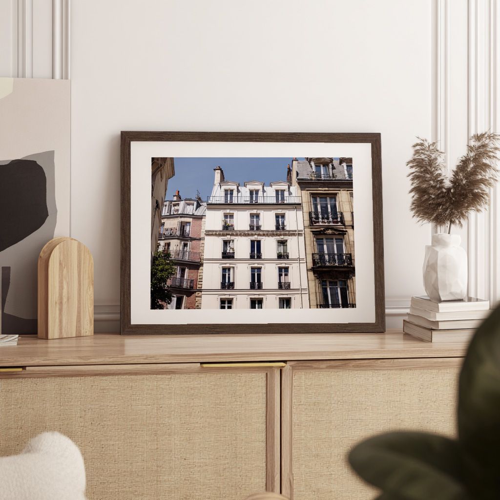 A framed photo of an elegant European building with balconies sits on a textured cabinet.