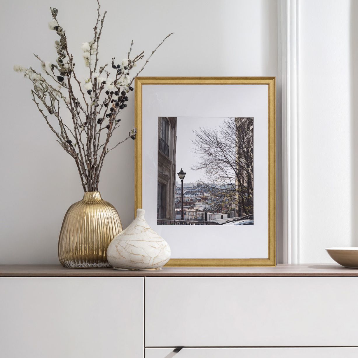 Stylized interior with gold-framed art depicting a snowy city street, and decorative objects.