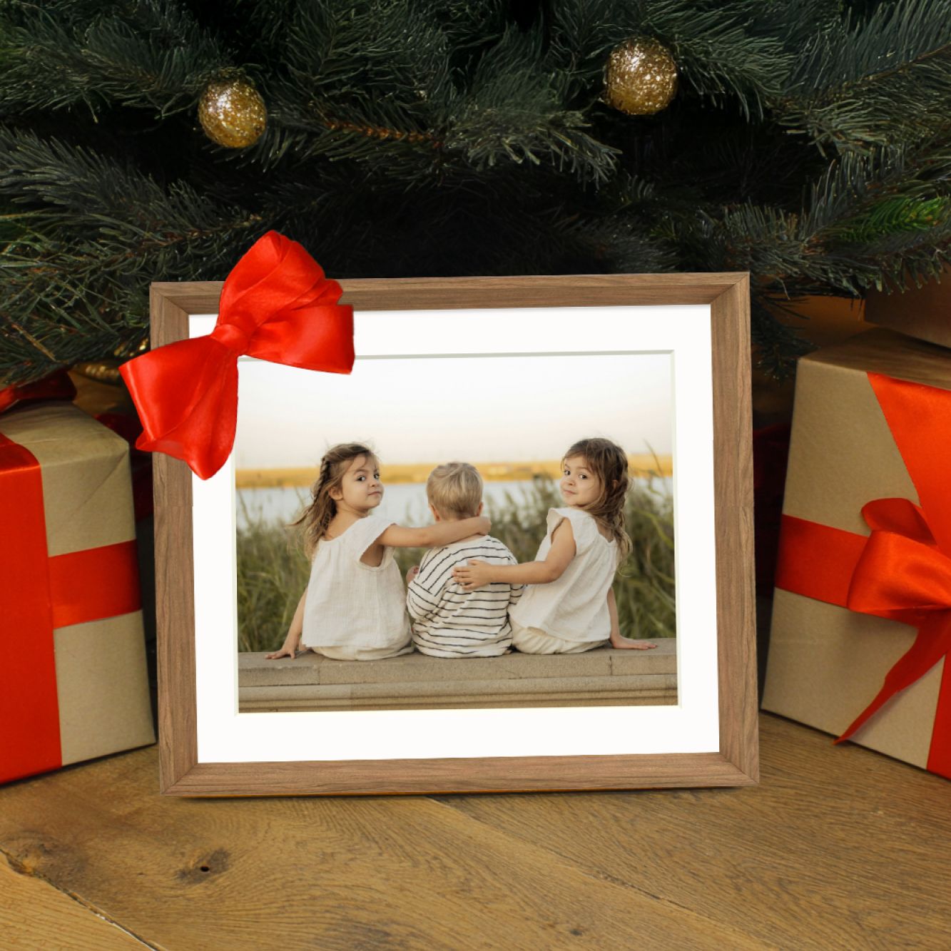 Framed photo of three children with a red bow, surrounded by Christmas gifts and a tree.